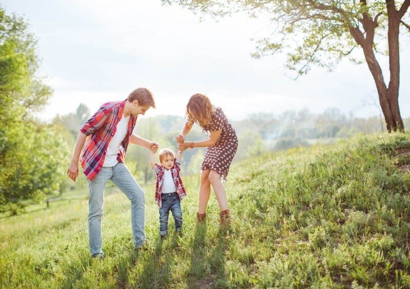 Parents and young child holding hands in the countryside