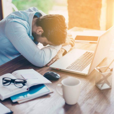 Man sat by desk with head slumped feeling unwell
